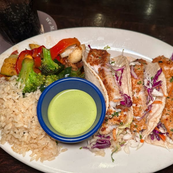 Mariano's fish tacos with rice, mixed vegetables, and a side of green sauce.