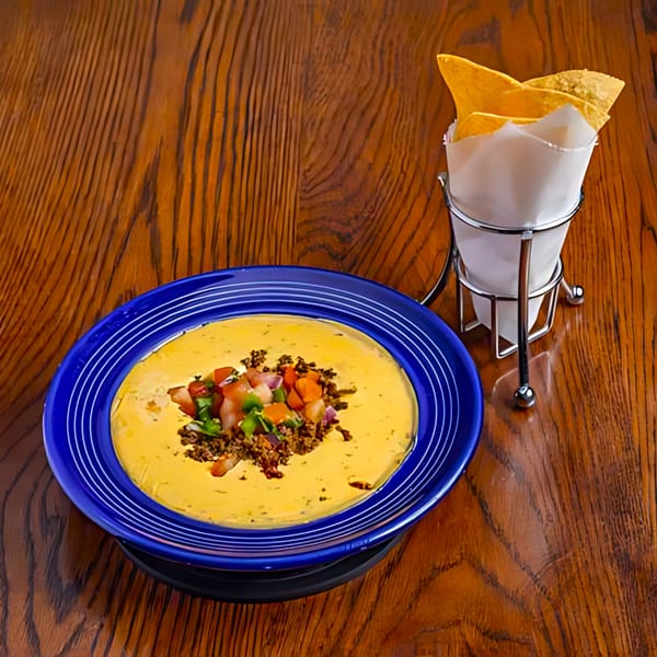 Mariano's queso with ground beef and pico de gallo, served with tortilla chips on a wooden table.