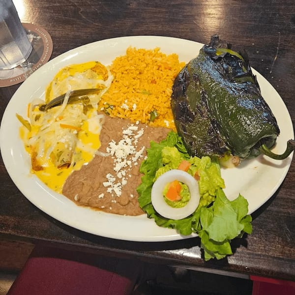 A Mariano's Mexican dinner plate with a large chile relleno, enchiladas, rice, refried beans, and salad.